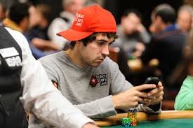 Image of a poker player scrolling through his cell phone, an example of attempted multitasking, while playing in a live poker game.