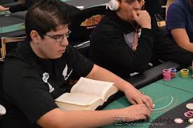 Image of a poker player reading a book while also playing live poker. An example of a player trying to multitask in a live poker game.